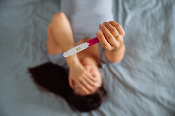 sad woman on bed with negative pregnancy test