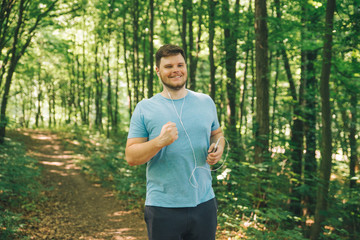 Naklejka na ściany i meble adult young man running in woods. copy space. smiling
