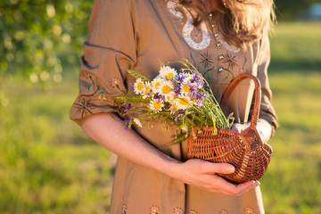 Midsummer in Latvia: celebration of Ligo - a young woman weave a wreath and collect field flowers