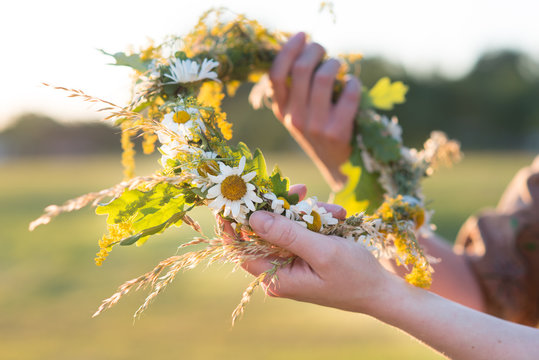 Midsummer in Latvia: celebration of Ligo - a young woman weave a wreath and collect field flowers