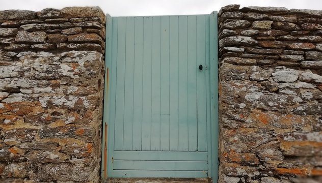 porte en bois bleu et mur en pierres sèches,entrée de jardin