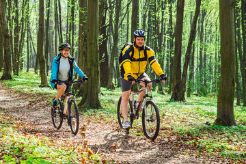 couple riding bicycle in forest in warm day