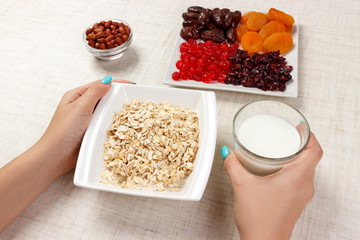 The girl took milk to pour it into oatmeal. Useful and healthy breakfast. White background