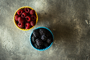 Raspberries and Blackberries in Ceramic Bowls on Rustic Background