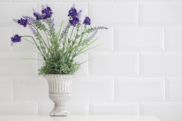 Flowers in a vintage vase are placed on a white table.