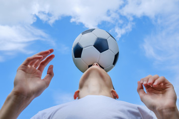 Teenage boy with a soccer ball on a of blue sky