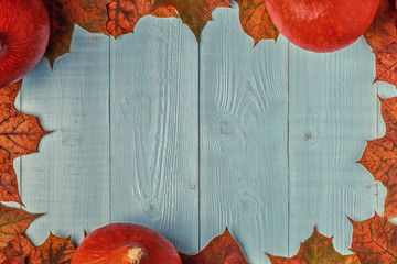 Autumn background with colored leaves and pumpkins on wooden background.