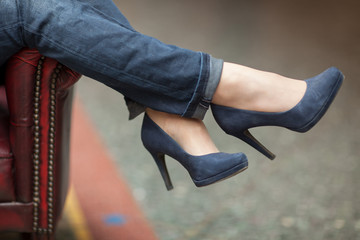 young woman's feet and legs close up in a street cafe, urban mood, blue jeans and high heels - 209909888