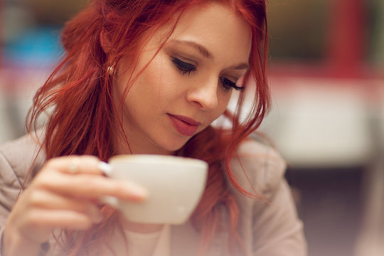 young beautiful woman in a street cafe enjoying a coffee, summerly urban mood