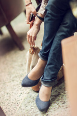 young woman's feet and legs close up in a street cafe, urban mood, blue jeans and high heels