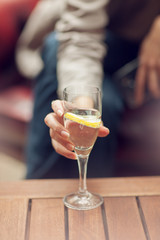 Young woman drinking a glass of water in a street cafe, close up on her hand holding glass, sunny urban mood
