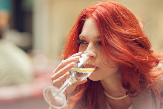 young attractive woman drinking a glass of water in a street cafe, sunny urban mood