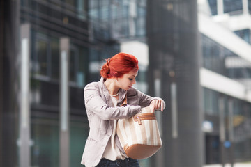 young beautiful business woman holding purse, working in downtown, outdoors