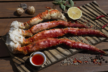 Fresh crab claws with sauce, pepper and lemon on vintage wooden background. 
