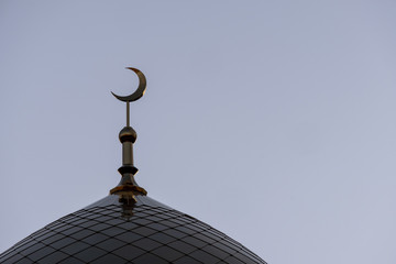 Fototapeta na wymiar The symbol of Islam is a golden crescent moon on top of the mosque minaret on the blue evening of the morning sky.