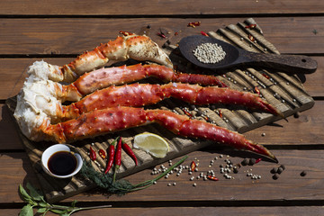Fresh crab claws with sauce, pepper and lemon on vintage wooden background. 
