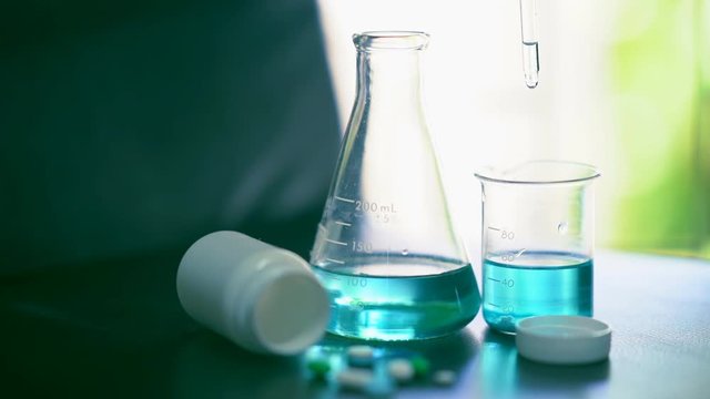 Bright slow motion chemical solution drpping on beaker for test chemical reaction of medicine on table