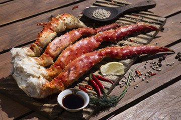 Fresh crab claws with sauce, pepper and lemon on vintage wooden background. 
