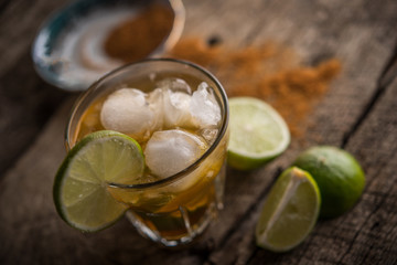 Ice tea with lime and cinnamon over rustic wood