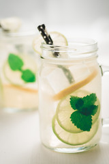 Fresh Mojito Cocktail with Cold Ice, Lemon and Mint Leaves in Mason Jar on White Wooden Background as Bright Summer Concept