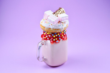 Pink strawberry freakshake with marshmallow and sweets.
