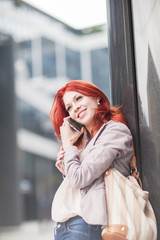 Fototapeta premium young beautiful business woman holdingmobile phone, working in downtown, outdoors