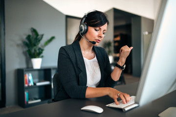 Support staff speaking with headset listening client problem in corporate office.