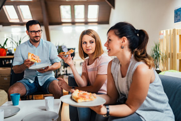 Coworkers eating pizza during work break at office.
