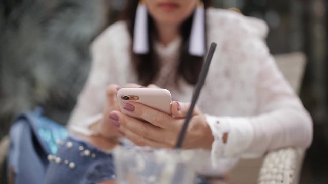 Girl in the cafe uses a smartphone close-up