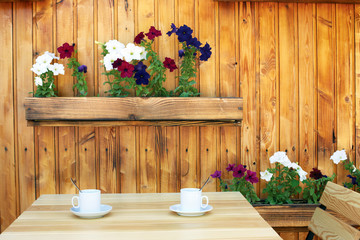 Empty wooden coffee terrace with flower pots table and chairs