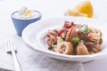 Greek Fried Squids Calamari with Red Chili Pepper and Fresh Mint Leaves on White Plate