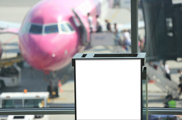 Pusty bilbord reklamowy na lotnisku na tle samolotu pasażerskiego.