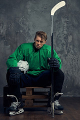 Professional hockey player rests after a hard workout sitting on wooden pallets on a gray...