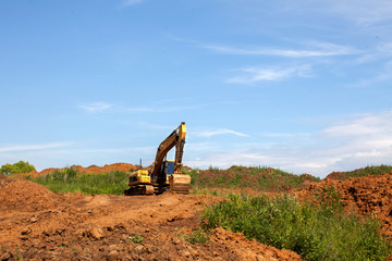 Fototapeta na wymiar Orange excavator is on a backround of blue sky.