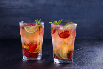 Strawberry mojito cocktail with berries, lime and mint. Summer berry cocktail on black background. horizontal