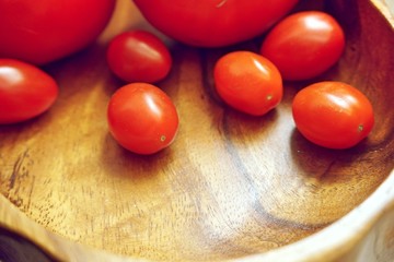 red cherry tomatoes in an olive bowl on a wooden table