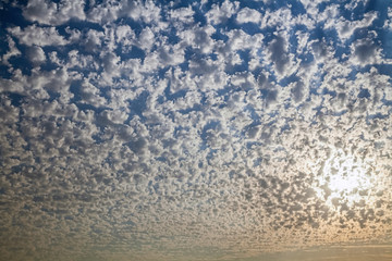 Uniform ornament of the shape of clouds against background of Sun.