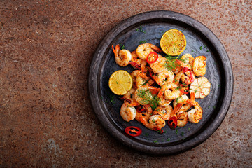 Prawns Shrimps roasted on  pan with lemon and garlic on dark rustic background. top view.