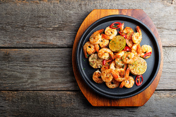 Prawns Shrimps roasted on  pan with lemon and garlic on dark rustic background. top view.