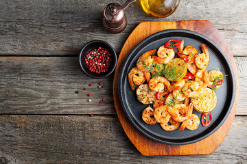 Prawns Shrimps roasted on  pan with lemon and garlic on dark rustic background. top view.