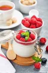 Delicious italian dessert panna cotta with raspberry sauce, fresh berries and mint on gray background.