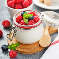 Delicious italian dessert panna cotta with raspberry sauce, fresh berries and mint on gray background.