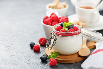 Delicious italian dessert panna cotta with raspberry sauce, fresh berries and mint on gray background. - obrazy, fototapety, plakaty