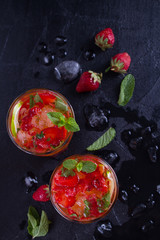 Strawberry mojito cocktail with berries, lime and mint. Summer berry cocktail on black background. overhead, vertical