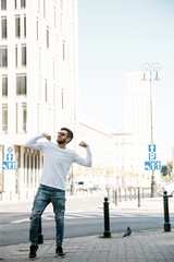 A young man travels through the streets of the city. Boy in sunglasses Stylish man near the building. The man sits on a whip. Beard and hair in a stylish guy.