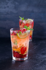 Strawberry mojito cocktail with berries, lime and mint. Summer berry cocktail on black background. vertical