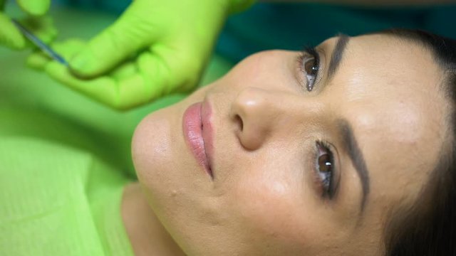 Dentist comparing color of sealant filling with patient natural teeth, closeup