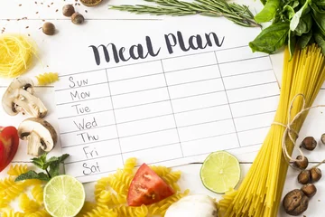 Foto op Canvas A meal plan for a week on a white table among products for cooking - pastas, basil, vegetables, lime, seeds, nuts and spices. Top view, flat lay, copyspace © svitlini