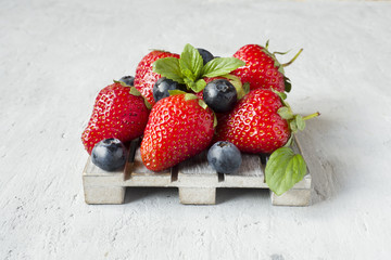 Fresh berries strawberries blueberries mint on a wooden stand, grey background with Copy space for...