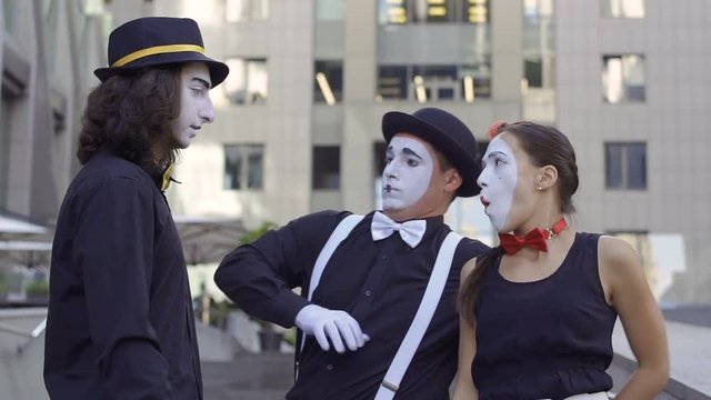 Three funny mimes have fun with each other in front of camera